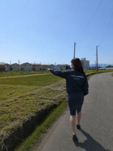 線路を指さして歩く女性の画像